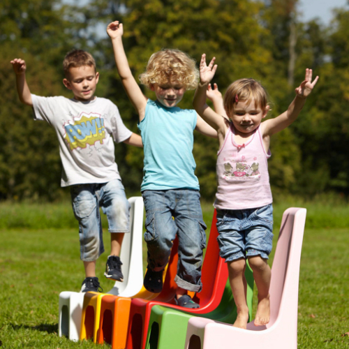 drei Kinder die über Kinderstühle laufen